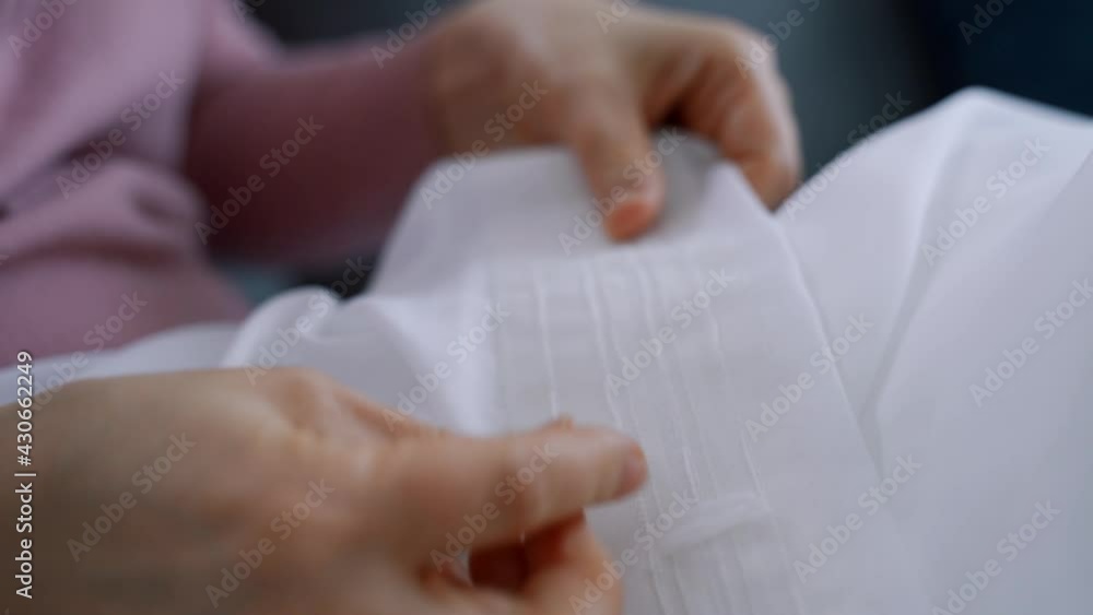 A woman sitting on the couch puts hooks on the Curtain tape. Housework on holiday. A woman sitting on the couch puts hooks on the Curtain tape. Housework on holiday.