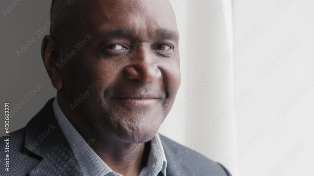 Portrait of african mature middle aged businessman afro black male wrinkled face standing in office looking out window planning lost in thought turns head nods waving positively answering yes agreeing Portrait of african mature middle aged businessman afro black male wrinkled face standing in office looking out window planning lost in thought turns head nods waving positively answering yes agreeing