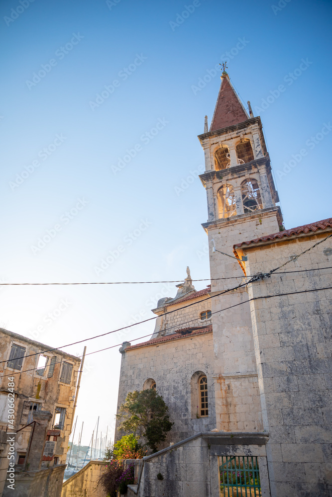 Bell tower of the Church of Our Lady of the Annunciation at the end of a narrow street in the town of Milna on Brac island, Dalmatia, Croatia