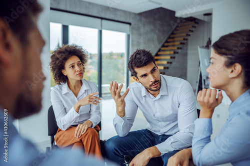 Photos Serious businessman sitting in circle with support group and talking about problems