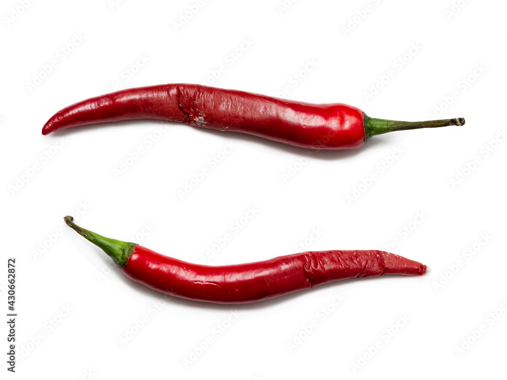 Two rotten, half-decomposed, limp vegetables on a white background. Spoiled, unhealthy spicy red capsicum (paprika). The concept of expired food, poisoning, infection.