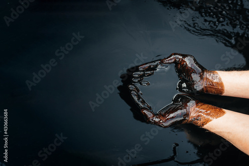 Caucasian oil hands are folded in a bowl of oil. Oil spill. Environmental pollution. an environmental disaster. Copy space photo