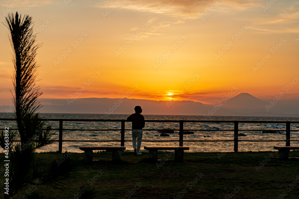 葉山の海の夕景　夕日が沈む海と富士山を眺める女性のシルエット　神奈川県立葉山公園