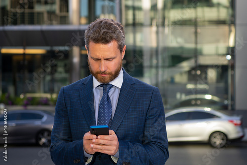 Portrait of businessman standing in a office. Businessman talking on phone. Portrait of cheerful Business man office worker talking on mobile phone while standing near modern office.