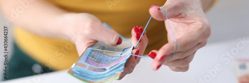 Woman binding euro cash with rubber band closeup