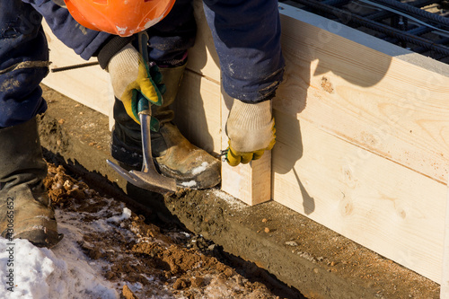 A worker hammers a nail at a construction site. Installation of wooden formwork. construction work photo