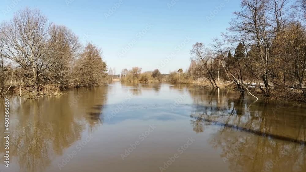 river flood, view from the bridge, brown water, current, blue sky, flooded trees, early spring river flood, view from the bridge, brown water, current, blue sky, flooded trees, early spring