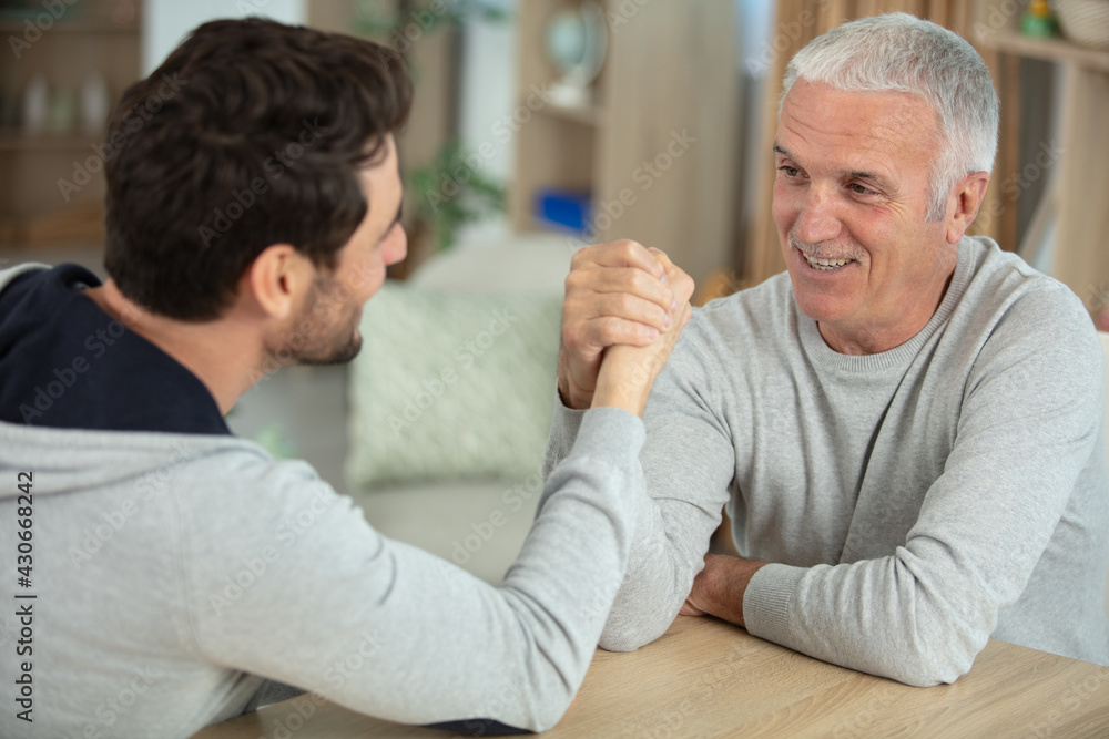 aged father and his handsome son competing in arm wrestling aged father and his handsome son competing in arm wrestling
