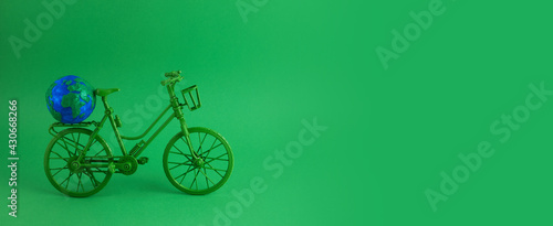 World bicycle day concept. Green bicykle with globe on green background. 3 june.