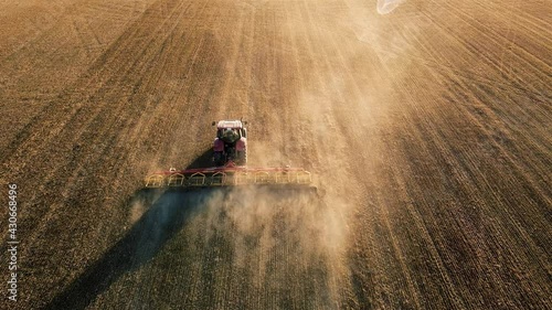 farm tractor with cultivator works the field aerial video