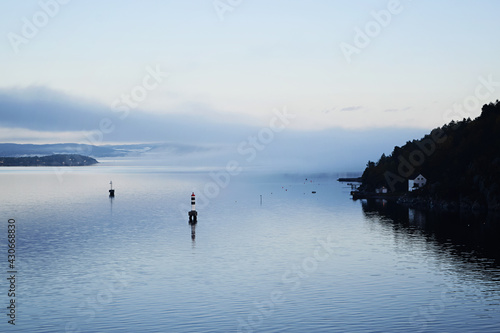 Early morning in the fjord with fog coming in over the calm water. Tranquil scene and beautiful landscape outside Oslo  Norway.