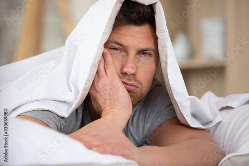 man sleepy drowsy unshaven bearded face covered with blanket photo