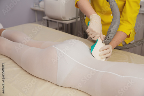 Woman in special white suit getting anti cellulite massage in a spa salon. LPG  and body contouring treatment in clinic.