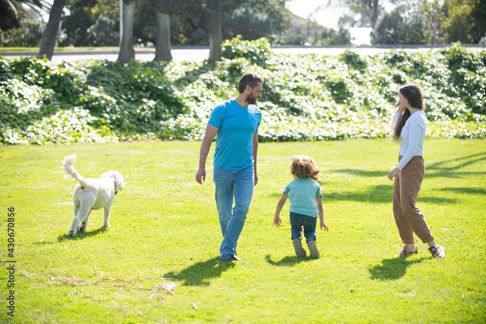 Happy child and parents with dog as family running in the nature. Young family with child having fun in nature.