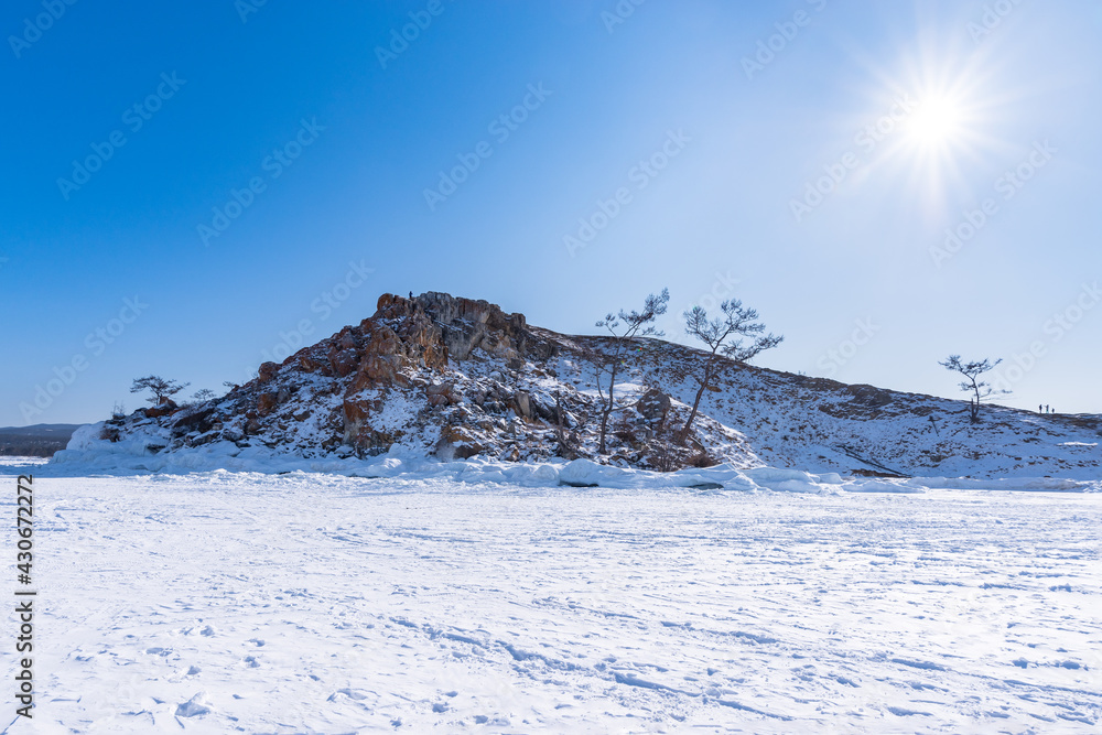 Sacred Cape Burkhan on Olkhon Island in winter. View from the ice of frozen Lake Baikal on a sunny day
