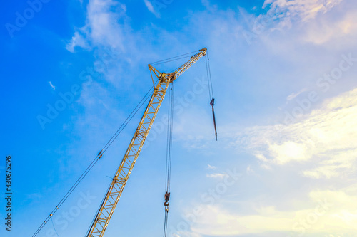 Hoisting machine industrial crane equipment against blue sky at construction site