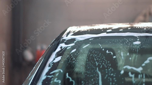 Black car sedan after washing in foam from side and back angles