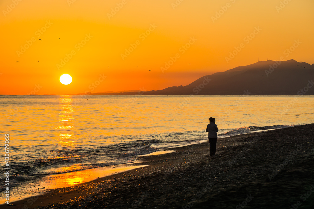 Silhouette of a woman on the Torre de Benagalbon beach (Andalusia, Spain), at sunset