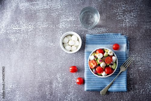 Mozzarella cucumber tomato red onion salad in a white bowl