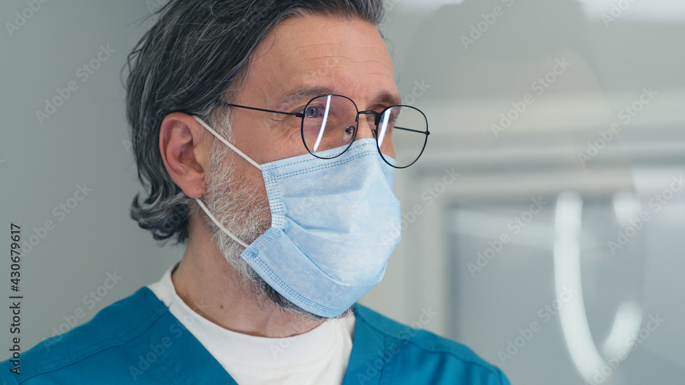 Mature doctor in mask speaking with patient on reception in medical center Mature doctor in mask speaking with patient on reception in medical center