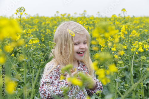 Outdoor candid portrait of cute blonde girl in field of yellow flowers.