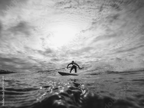 Canvas Print Surfer riding a wave on a cloudy day. Black and white ocean