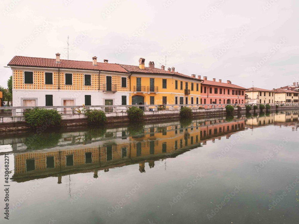 Picturesque colorful houses in Gaggiano, reflected in the navigable canal called Naviglio Grande, near Milan.Lombardy, Italy.