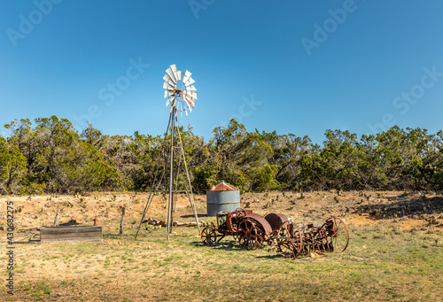 Old rusty tractor and a windmill on the backroads of Texas photo