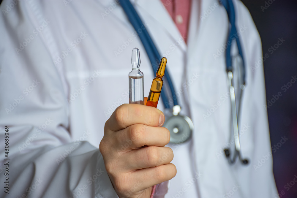 Idea of photo treating diseases with injectable drugs or offering a drug to pharmacist or doctor. A medical worker holds two vials of liquid medicine for intramuscular intravenous injection Idea of photo treating diseases with injectable drugs or offering a drug to pharmacist or doctor. A medical worker holds two vials of liquid medicine for intramuscular intravenous injection