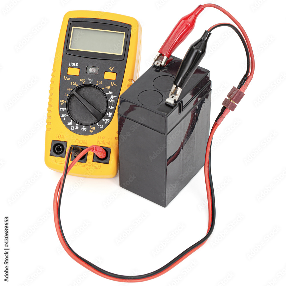 Testing an acid rechargeable battery with a measuring instrument isolated on white background Testing an acid rechargeable battery with a measuring instrument isolated on white background