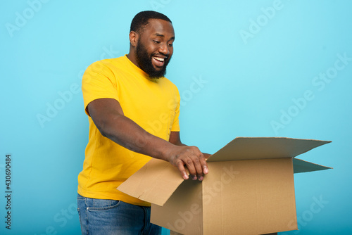Happy man receives a package from online shop order. happy expression. Blue background.