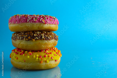 Berliner donuts lie on top of each other on a blue bright background with a place to text and a copy of the stillure picture of a meal on the table