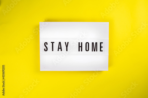 Lightbox with text message STAY HOME isolated on yellow background. Concept of self isolation distancing, quarantine because of covid19 pandemic, health care, people protection, coronavirus new normal