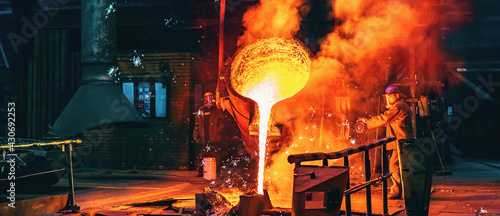 Liquid iron molten metal pouring in container, industrial metallurgical factory, foundry cast, heavy industry background. photo