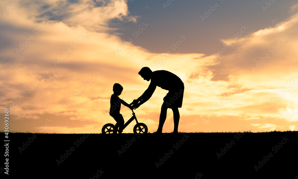 Father teaching his son to rid bicycle. Parenting and childhood concept. 
