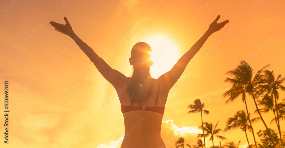 Happy woman lifting ams up to the sky in a beautiful tropical nature setting. 