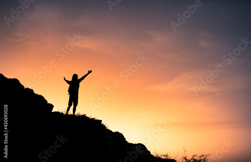 silhouette of a man on top of the mountain with arms outstretched 