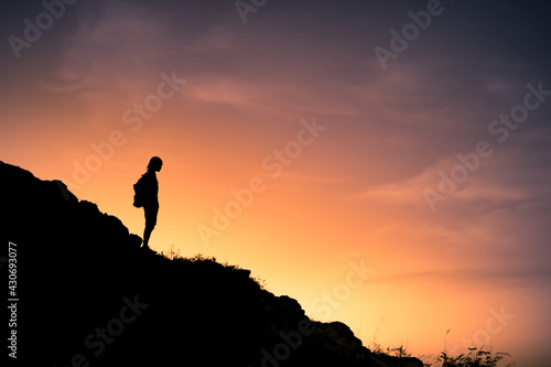 Man hiker standing on a mountain edge looking at the view. 