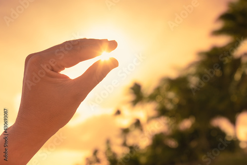 Hand holding the sun between fingertips. Spirituality, and beauty in nature. 