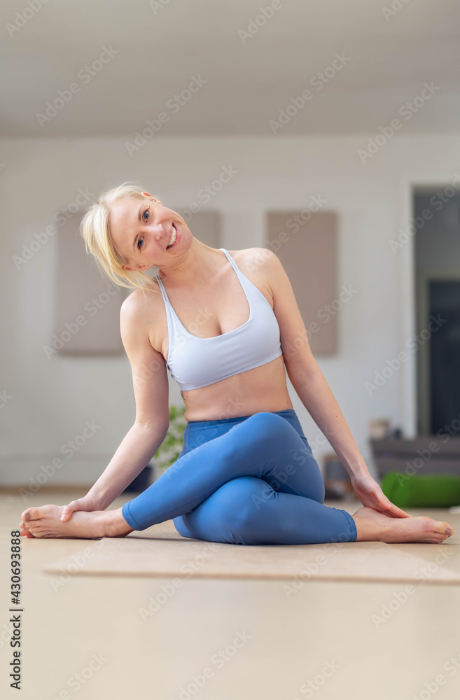 Vertical Shoot of a Young woman stretches, after a yoga session, in her empty studio, closed for the corona virus. Looking at the camera smiling and whit serene expression. Vertical Shoot of a Young woman stretches, after a yoga session, in her empty studio, closed for the corona virus. Looking at the camera smiling and whit serene expression.