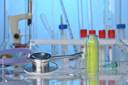 Medical lab desk with chemical glassware and stethoscope. Test tubes, fluid flasks, medical gadgets in chemical laboratory. Biotech research laboratory with biochemicals on the desk. Science center.