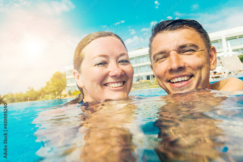 happy young couple resting in swimming pool and smiling at camera happy young couple resting in swimming pool and smiling at camera
