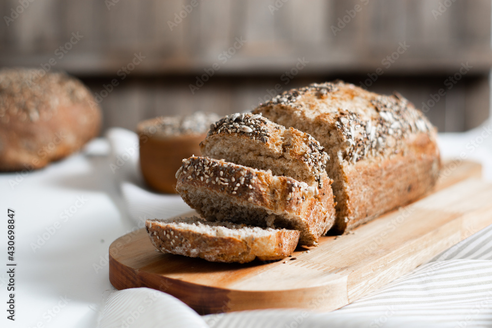 Selective focus. Slices of homemade wholemeal seed bread in the kitchen with rustic wooden background. Horizontal