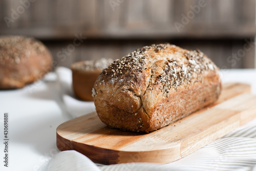 Selective focus. Homemade whole grain bread with seeds in the kitchen with rustic wooden background