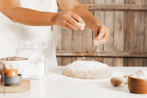 Female chef making shower of flour and ingredients for the dough on the kitchen table.