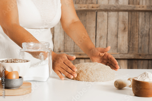 Woman's hands making a dough for a homemade bread, rustic wooden background.