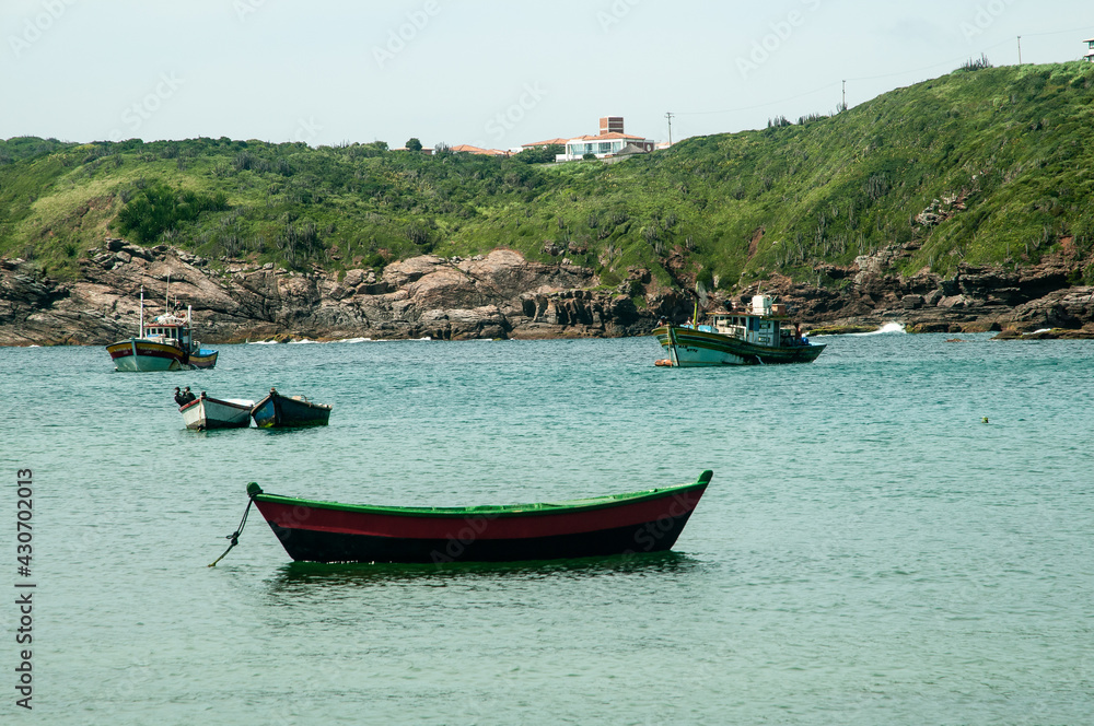 Boats and canoes anchored on water in a bay.