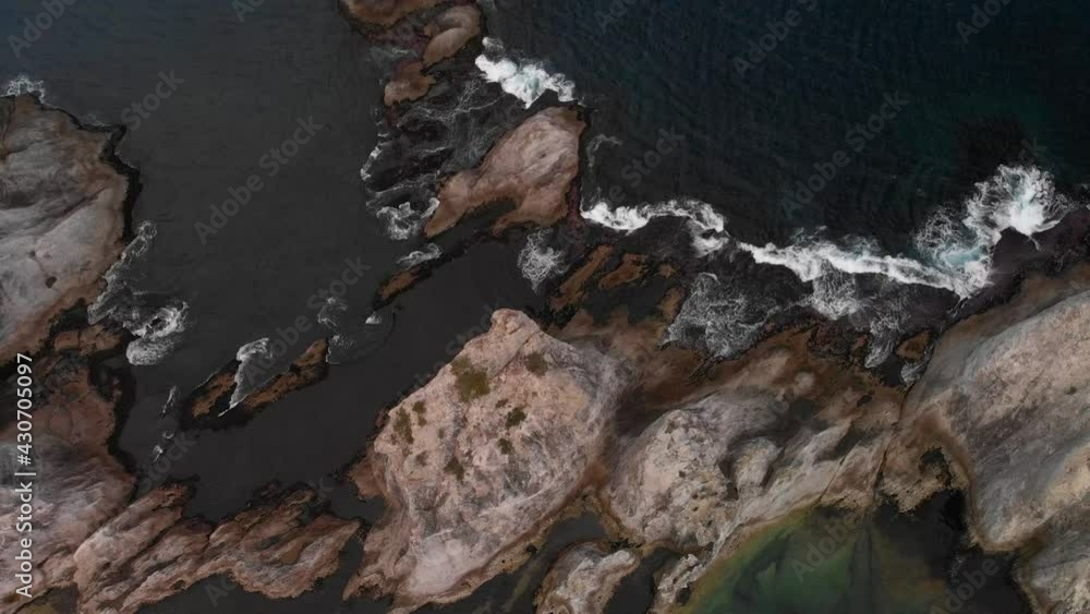 Top down aerial over tall cliffs with breaking waves during rough weather Top down aerial over tall cliffs with breaking waves during rough weather