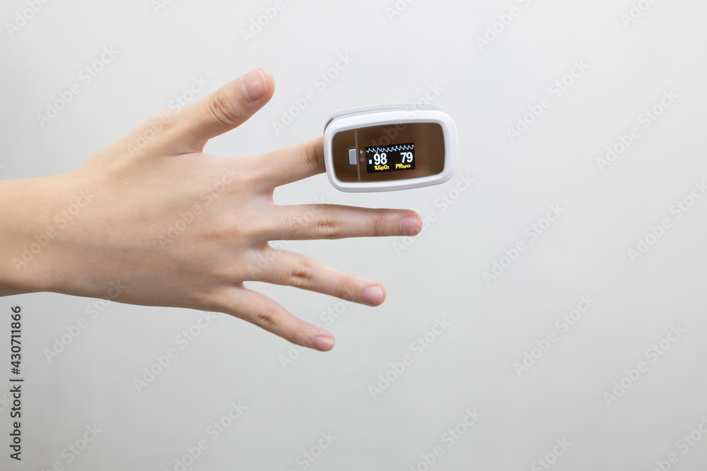 Hand of asian child girl with an attached pulse oximeter on fingertip,lady measuring heart rate,checking oxygen saturation level in the blood,diagnosis of Coronavirus or COVID-19 at home,health care. Hand of asian child girl with an attached pulse oximeter on fingertip,lady measuring heart rate,checking oxygen saturation level in the blood,diagnosis of Coronavirus or COVID-19 at home,health care.