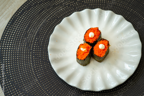 Salmon eggs or Ikura in Japanese style sushi fresh from raw salmond fish served on a white plate on dark background. photo